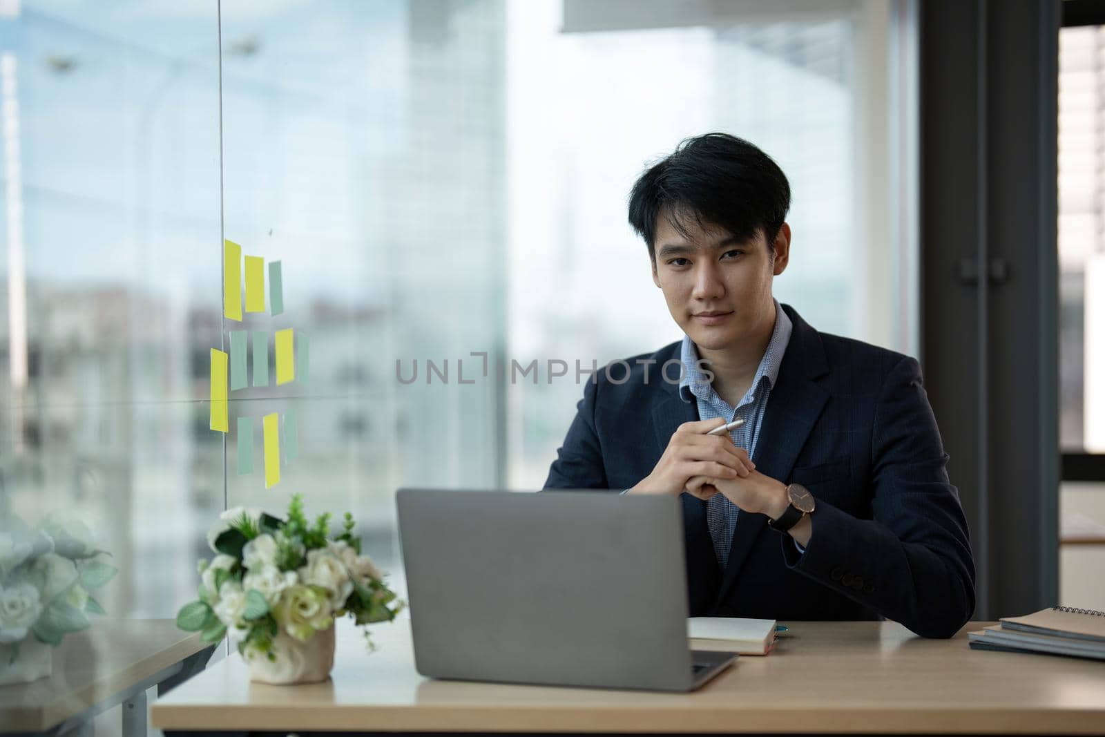 Young asian businessman smiling while working with laptop computer at office, business office concept.