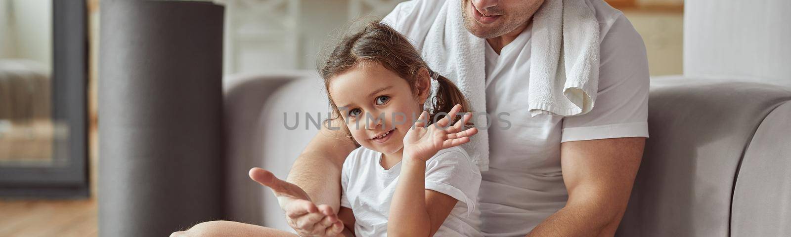 Smiling girl playing with father in living room by Yaroslav_astakhov