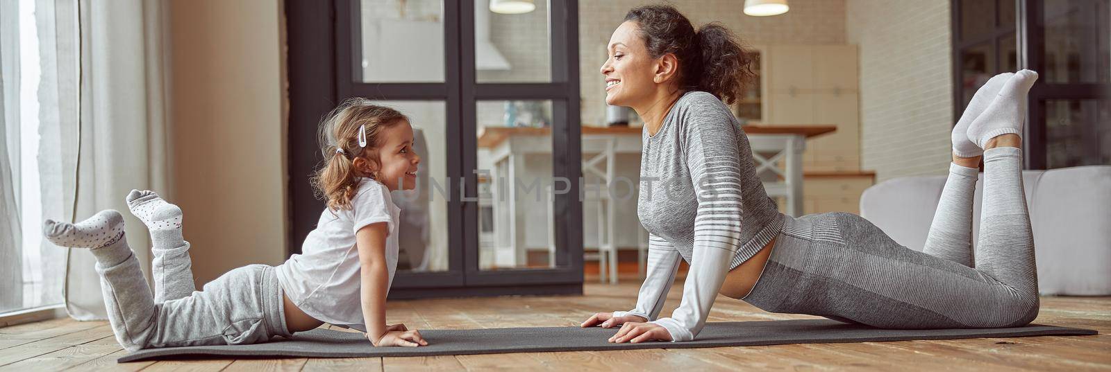 Happy mother doing stretching with little daughter at home by Yaroslav_astakhov