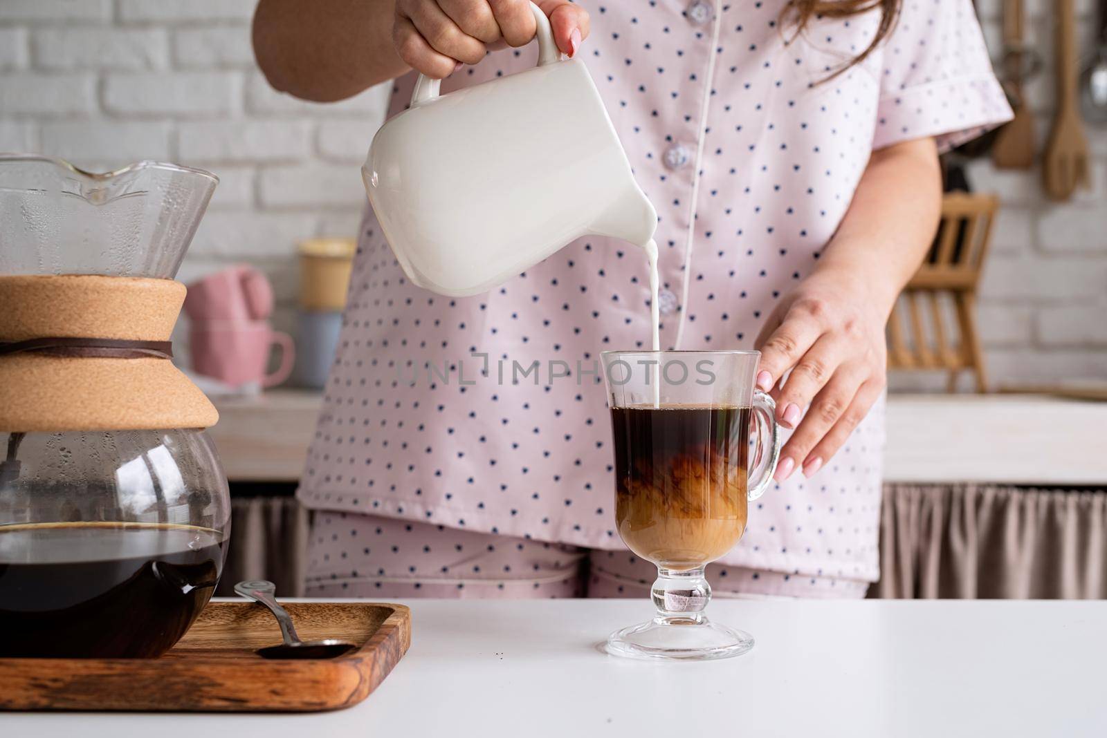 young woman in lovely pajamas making coffee at home kitchen by Desperada