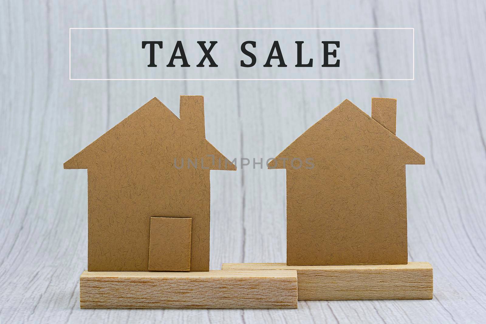 House brown paper model on white wooden background. Property investment and tax concept.