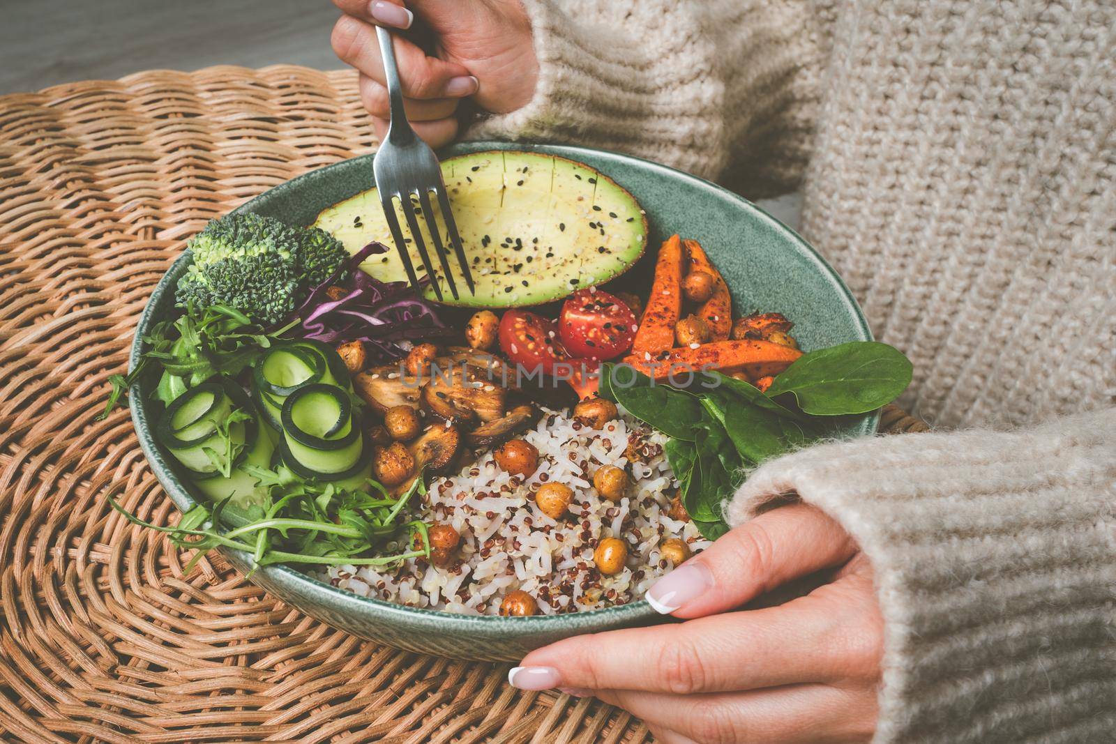 Woman eating healthy buddha bowl. Buddha bowl with rice, quinoa, avocado and vegetables. High quality photo