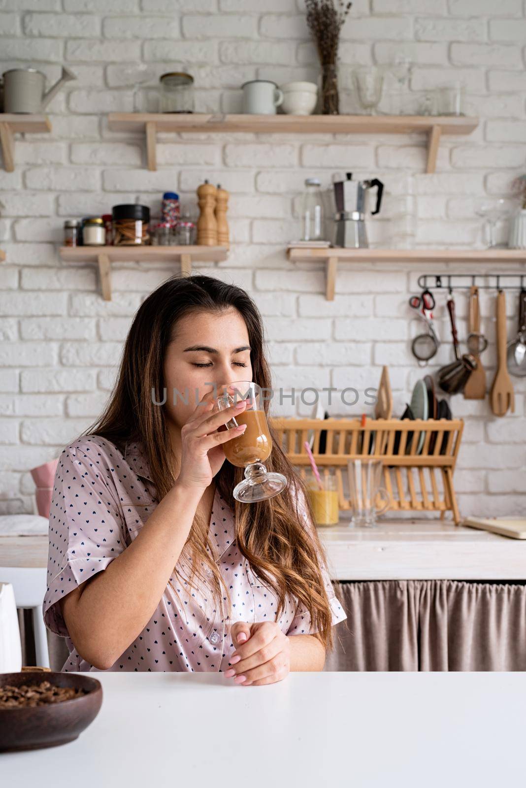 Alternative coffee brewing. young woman in lovely pajamas drinking coffee with milk at home kitchen