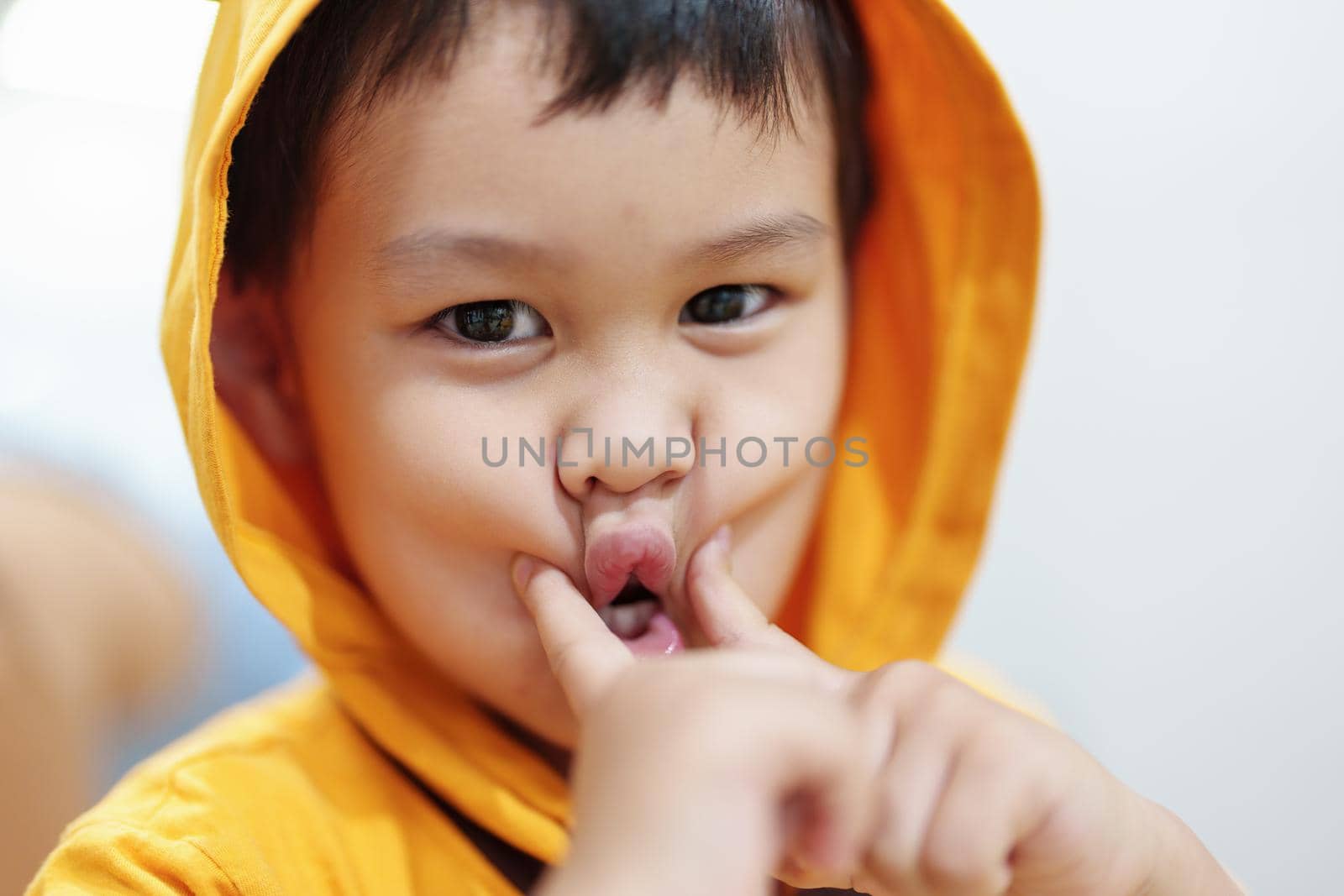 The cute eyes of an Asian boy wearing a hat is smiling and playing with innocence. by Manastrong