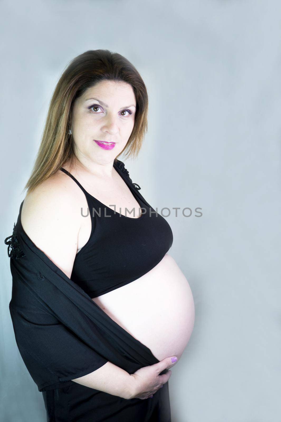 Eight month pregnant woman with bare belly. Happy emotion