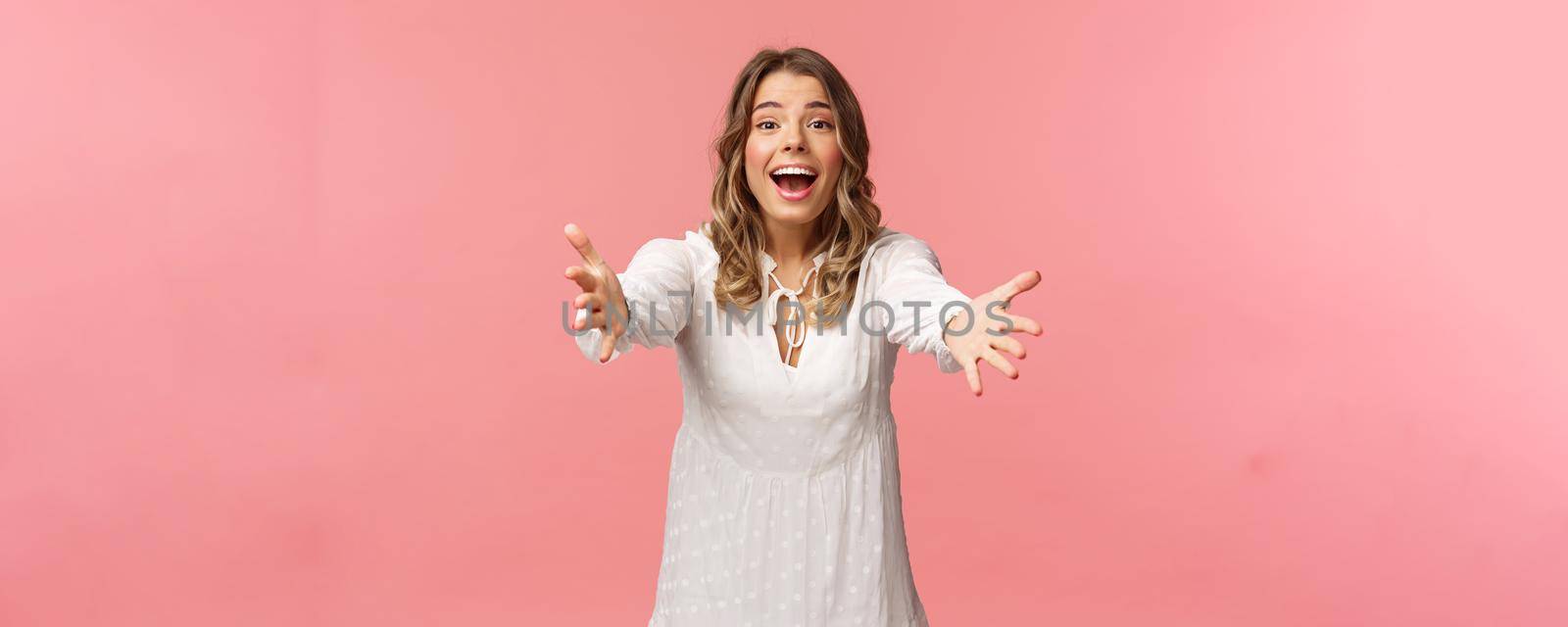 Come into my arms. Passionate cute blond girl in beautiful dress, reaching hands forward, catching something precious, attend wedding of friend, smiling excited, stretching arms, pink background.