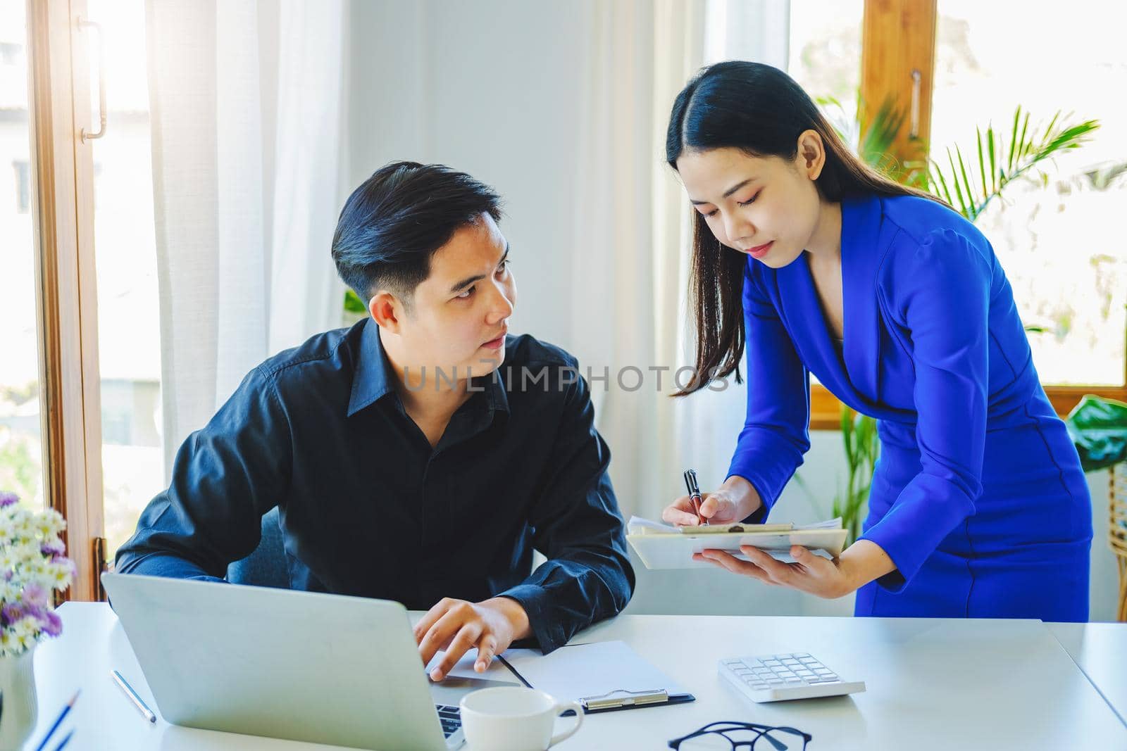 negotiation, analysis, discussion,asian female economist pointing out a document explaining the investment finance program to the company owner to plan marketing and hedging business risks. by Manastrong