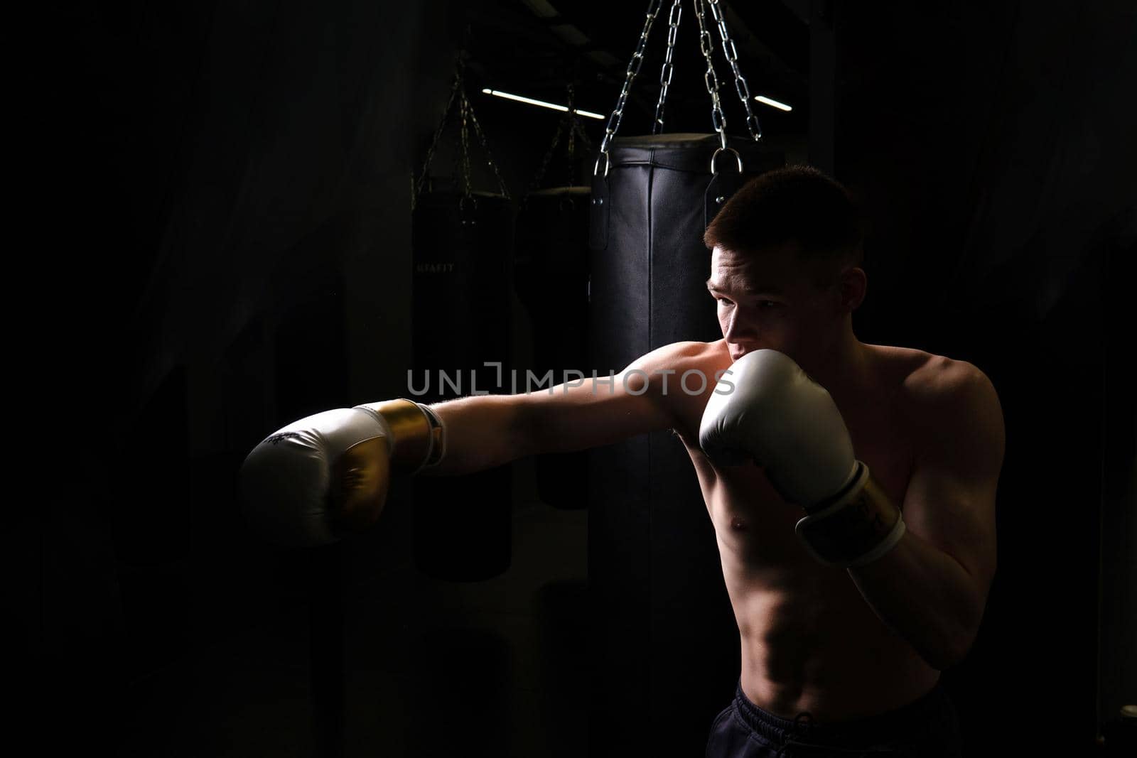 Athlete practices the The bag boxer blows glove black young professional boxing, In the afternoon strong gloves for punch and fist competitive, training sweat. Athletic model box, sexy