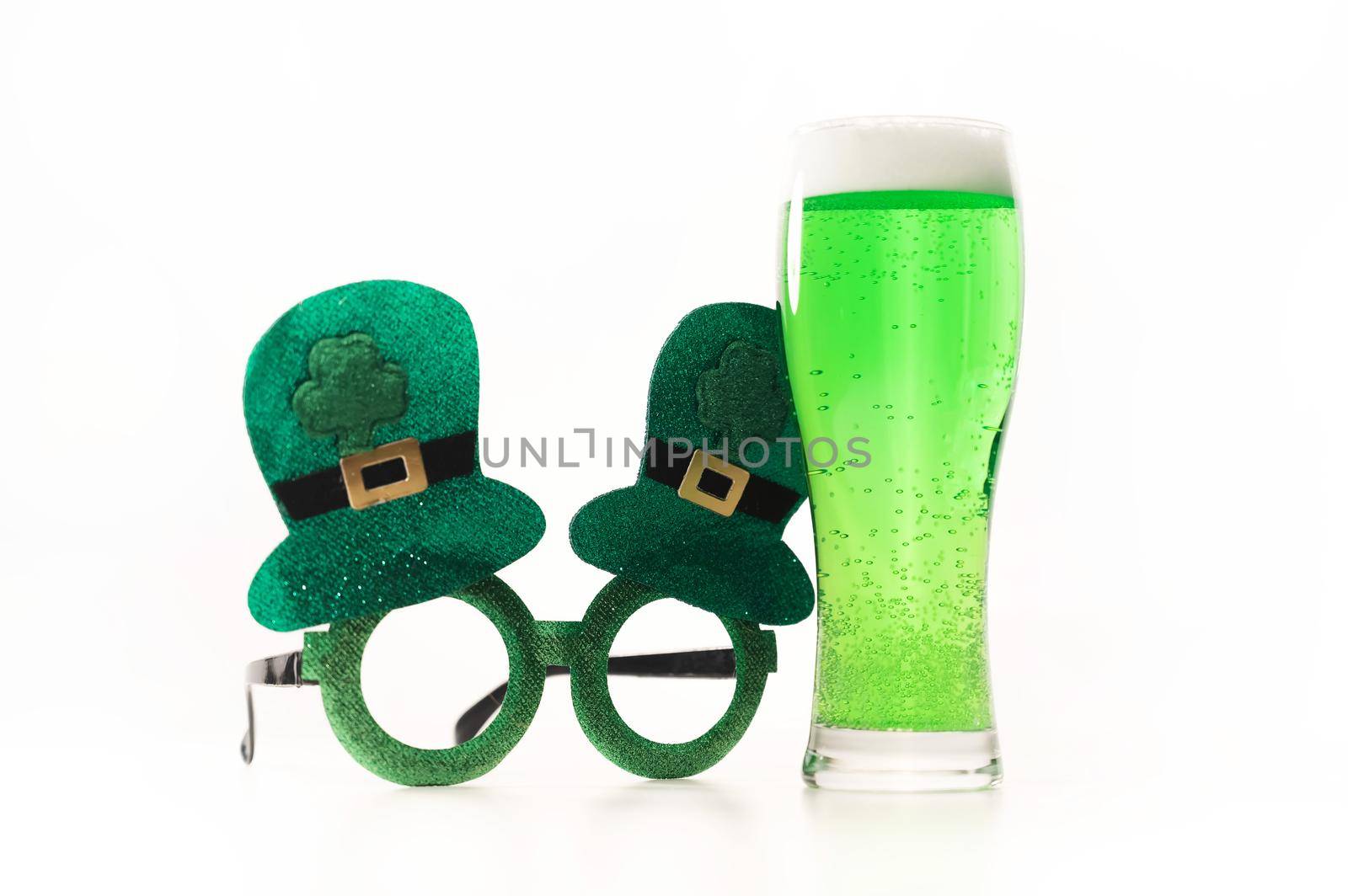 A glass of green beer and funny glasses for st patrick's day on a white background. Traditional Irish drink for a holiday by mrwed54