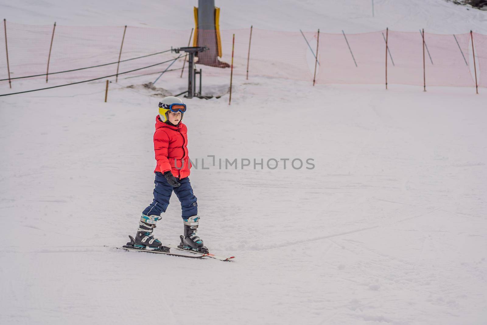 Child skiing in mountains. Active toddler kid with safety helmet, goggles and poles. Ski race for young children. Winter sport for family. Kids ski lesson in alpine school. Little skier racing in snow.