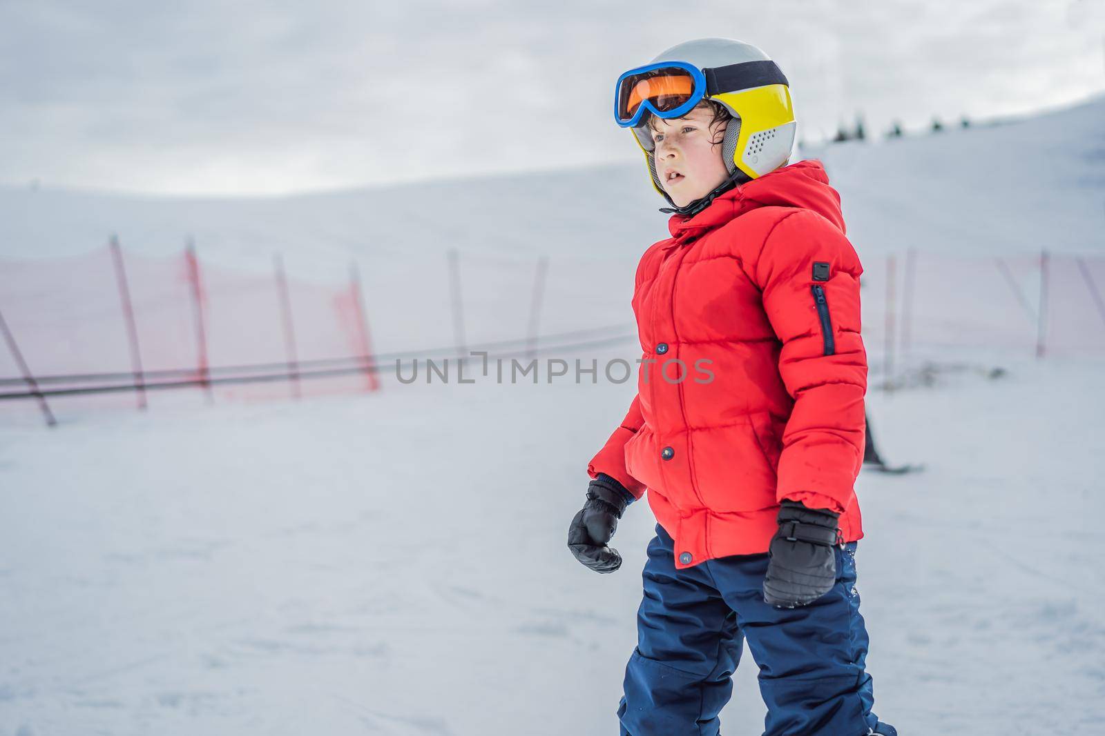 Child skiing in mountains. Active toddler kid with safety helmet, goggles and poles. Ski race for young children. Winter sport for family. Kids ski lesson in alpine school. Little skier racing in snow.