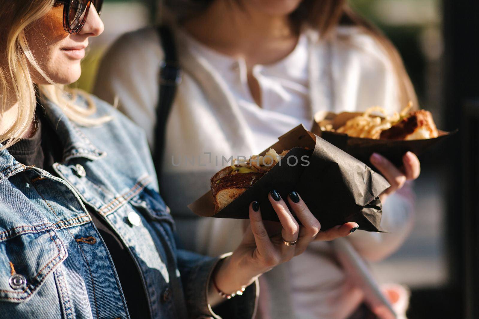 Tasty hot-dog in female's hands. Girls buy street food.
