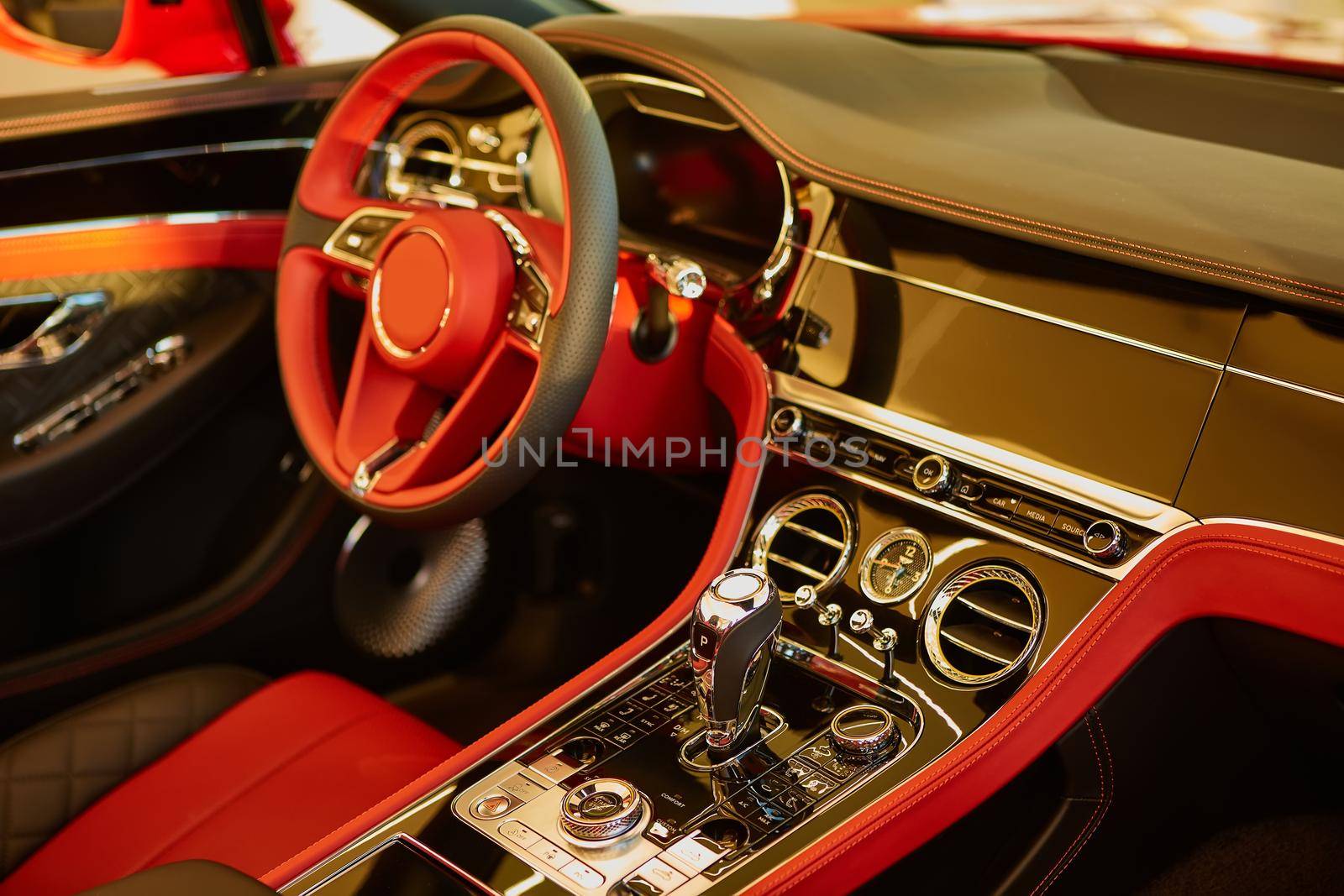 Red luxury car Interior. Steering wheel, shift lever and dashboard. Shallow doff.