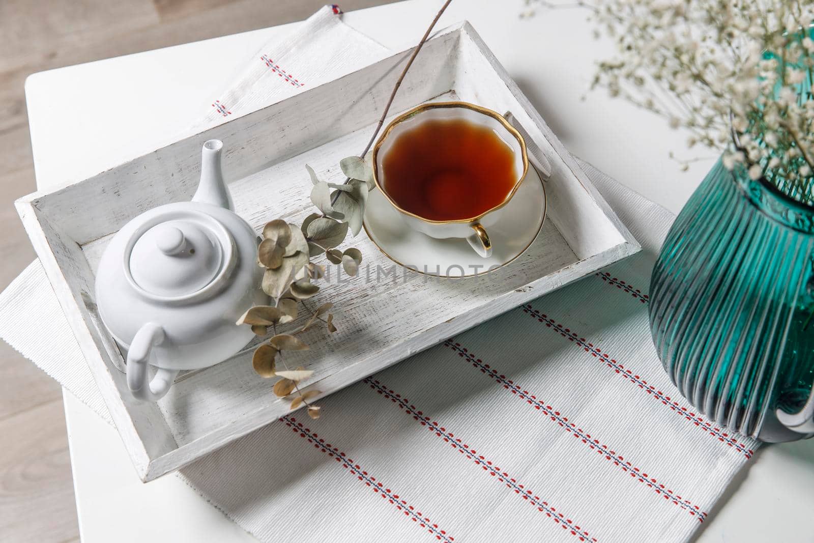 interior and home coziness concept. Top view. A cup of tea, a teapot with herbal tea, sugar bowl on a wooden white tray on the table. Porcelain cup by elenarostunova