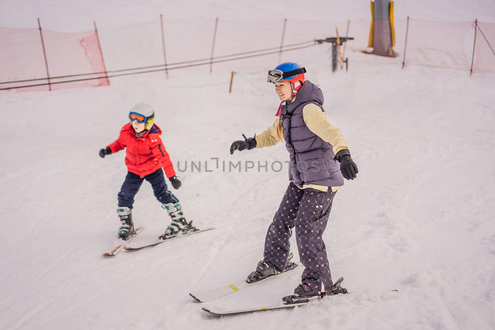 Mom and little boy mountain ski standing on top of the peak piste with high mountains on background by galitskaya