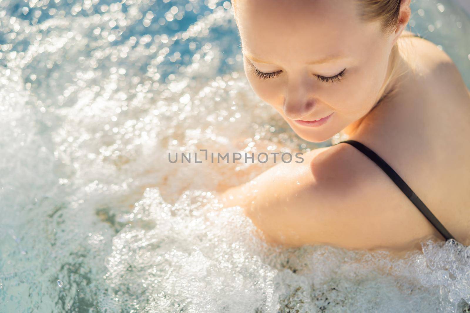 Portrait of young carefree happy smiling woman relaxing at hot tub during enjoying happy traveling moment vacation life against the background of green big mountains.