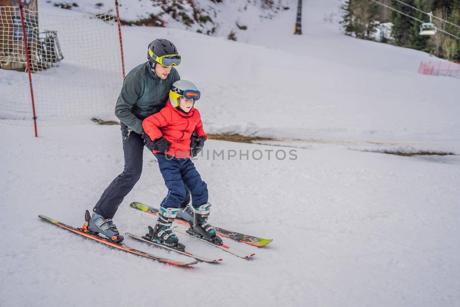 Boy learning to ski, training and listening to his ski instructor on the slope in winter by galitskaya