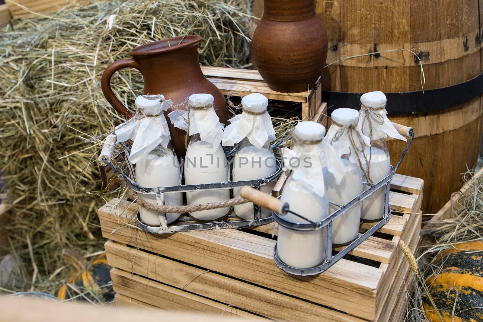 Milk - decoration on farm. Agriculture, farming. Farmer milk in bottles. Natural milk, organic milk. Vintage ornament with hay, straw and bottles with yogurt. Farmer product. Rustic decor. Products by elenarostunova