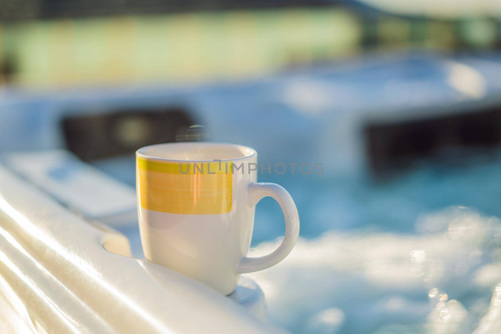 Mug with morning drink on the side of Hot tub hydromassage pool. Illuminated pool. Rest outside the city. Cottage with hydromassage pool.