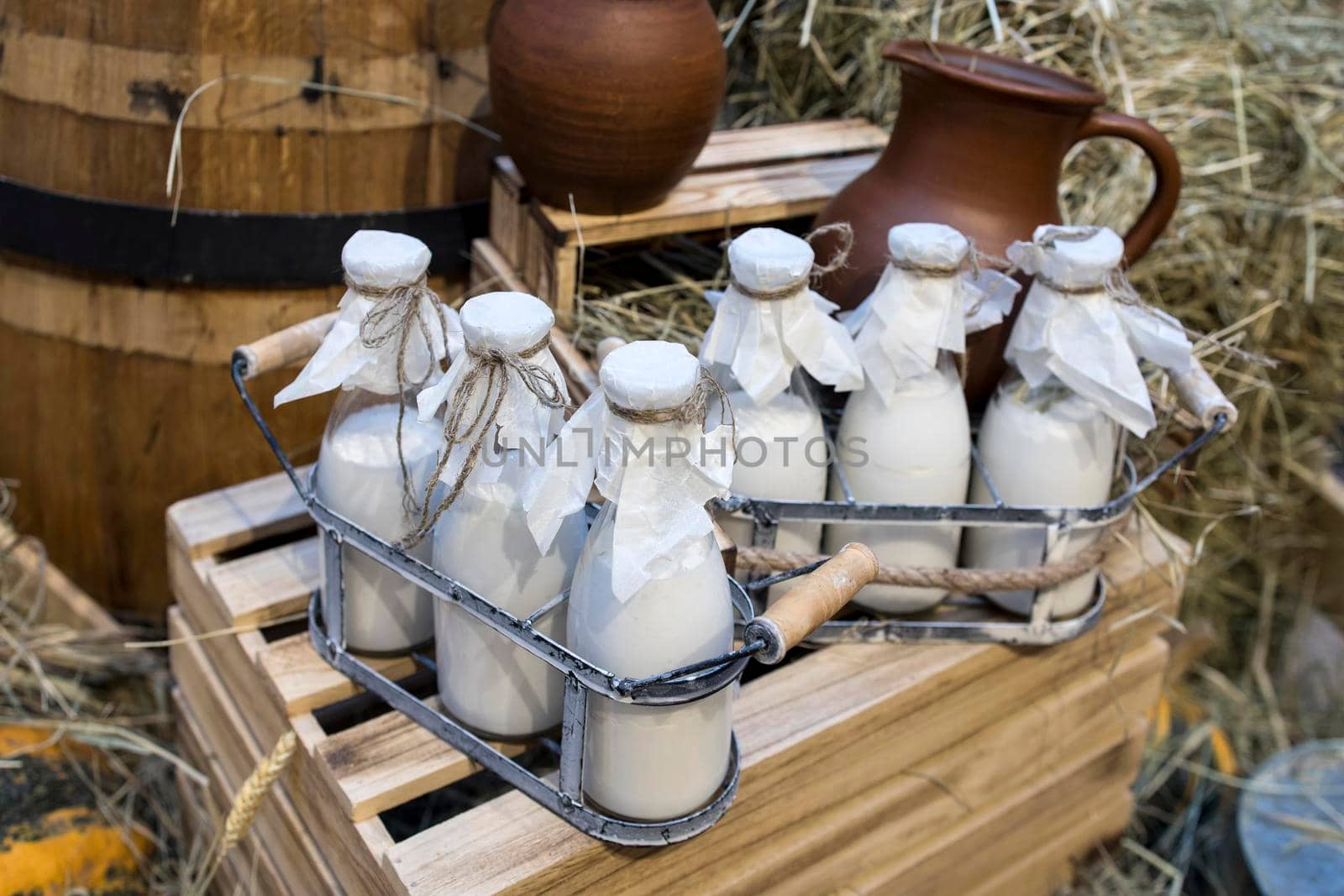 Milk - decoration on farm. Agriculture, farming. Farmer milk in bottles. Natural milk, organic milk. Vintage ornament with hay, straw and bottles with yogurt. Farmer product. Rustic decor. Products