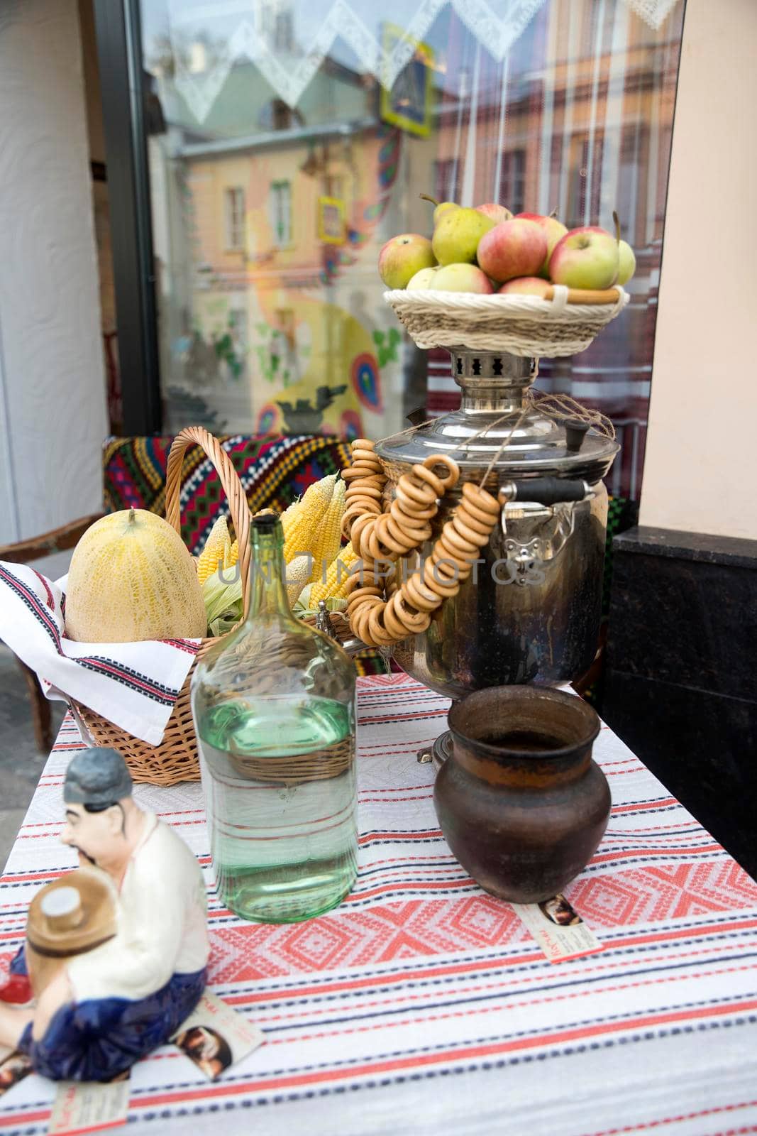 Table decoration - a bottle of Ukrainian vodka, a samovar, a basket of apples, bagels on a rope, embroidered towels, a clay pot, a sculpture of a Ukrainian.