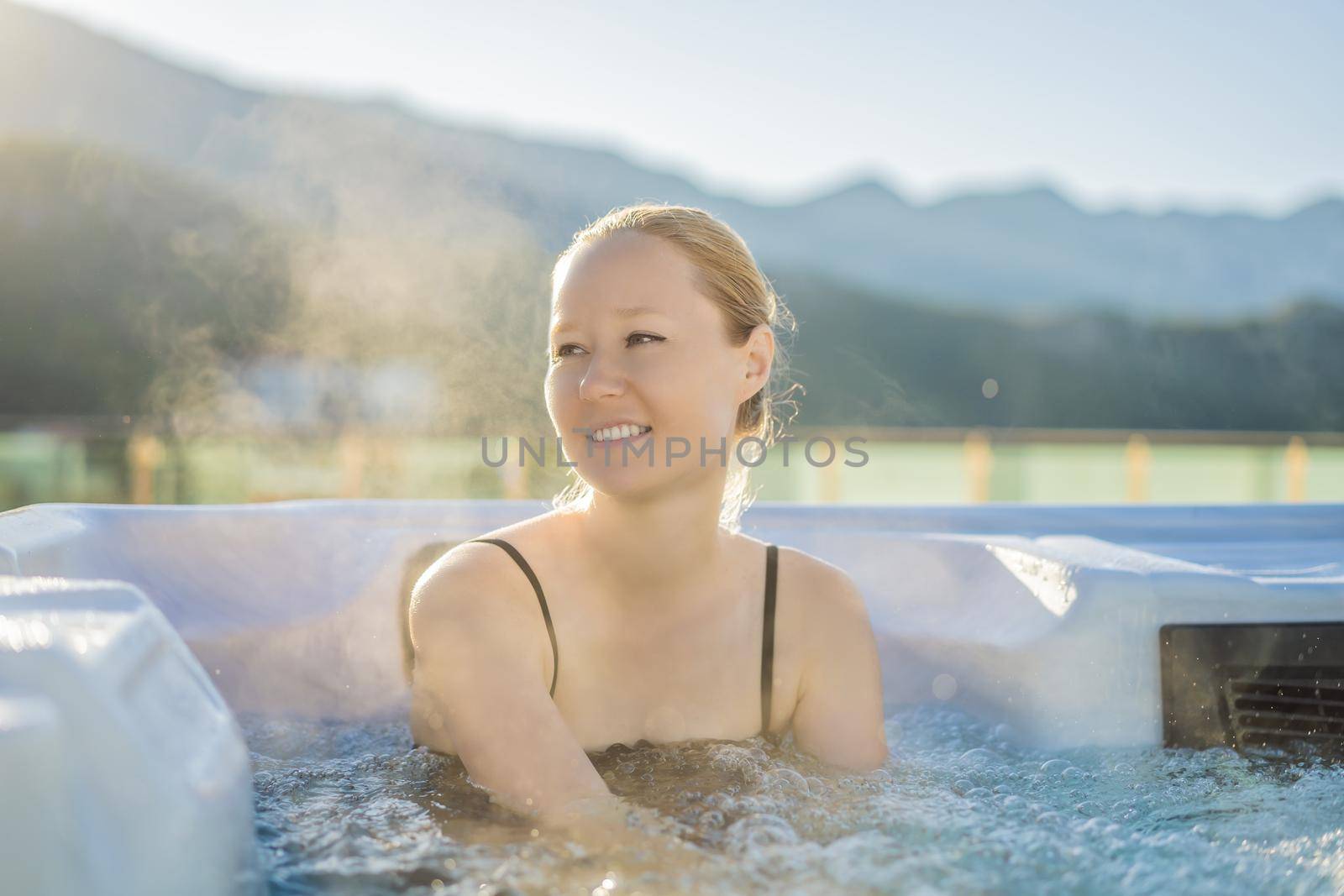 Portrait of young carefree happy smiling woman relaxing at hot tub during enjoying happy traveling moment vacation life against the background of green big mountains.