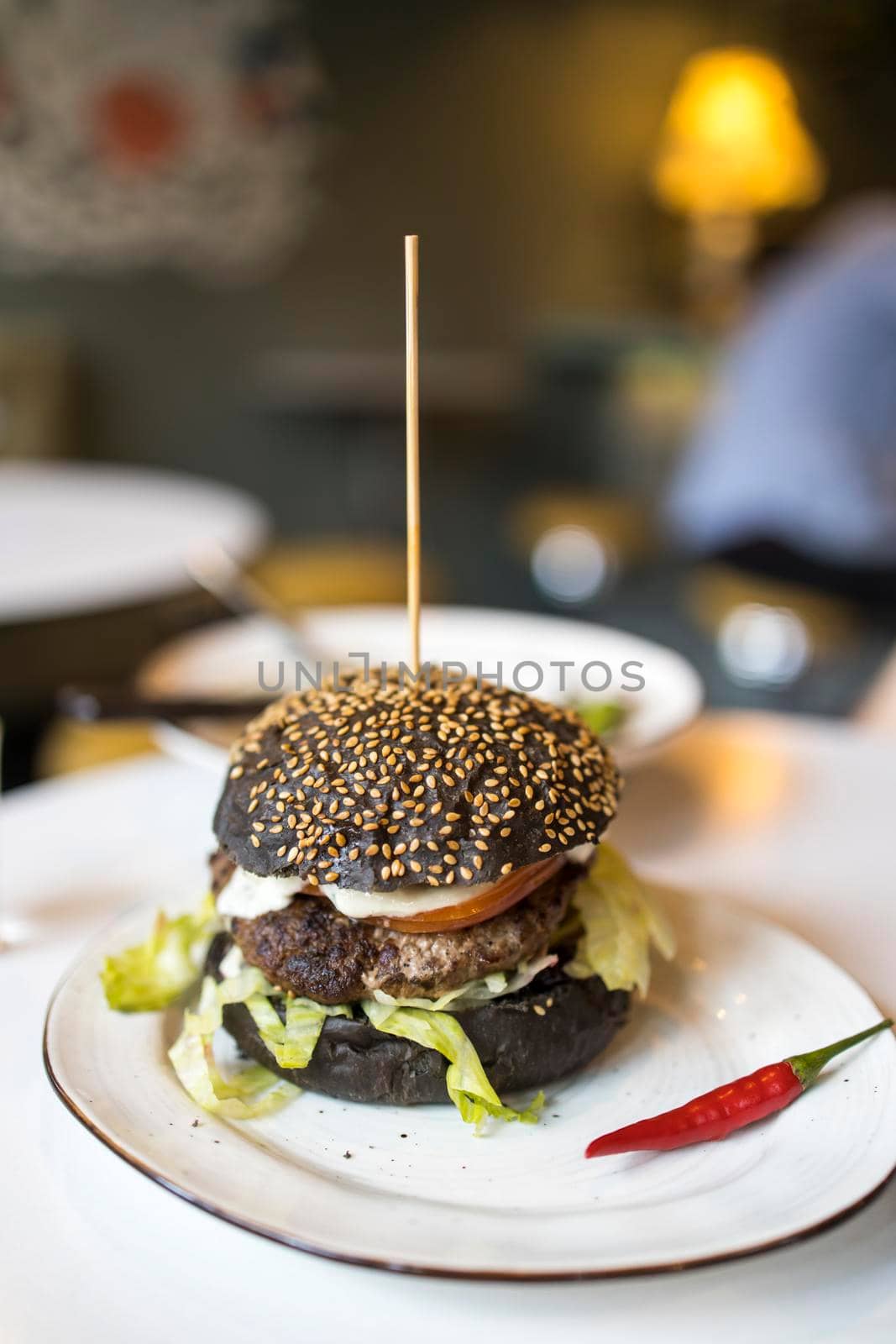 Black flour burger on a plate with red hot peppers on a plate