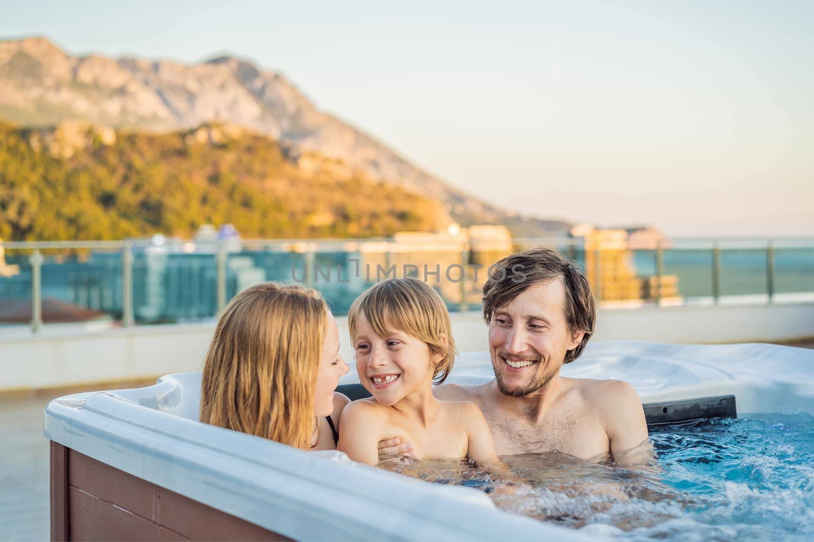Portrait of young carefree happy smiling happy family relaxing at hot tub during enjoying happy traveling moment vacation. Life against the background of green big mountains by galitskaya
