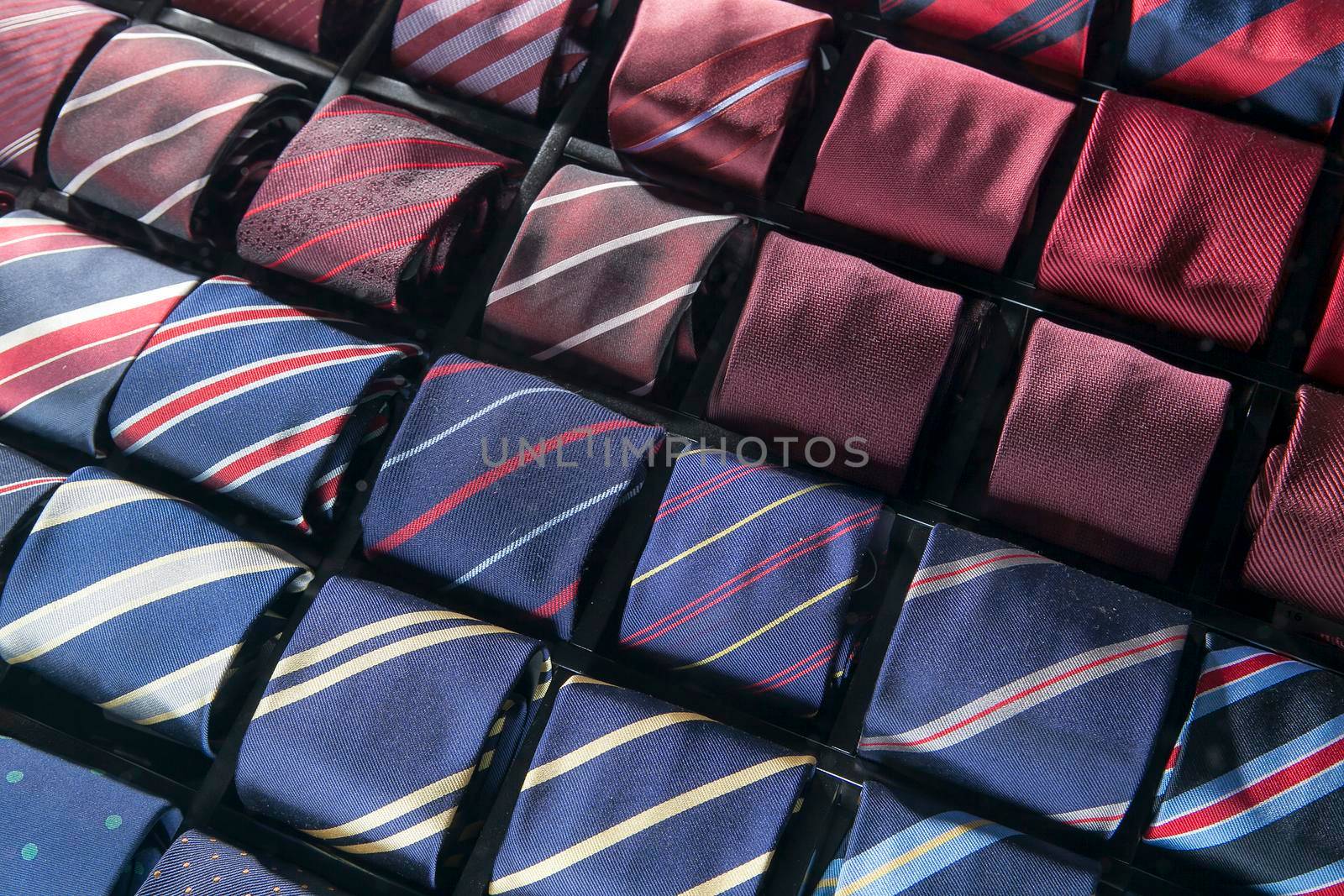 Men's silk ties are laid out from burgundy to blue in special compartments for ties