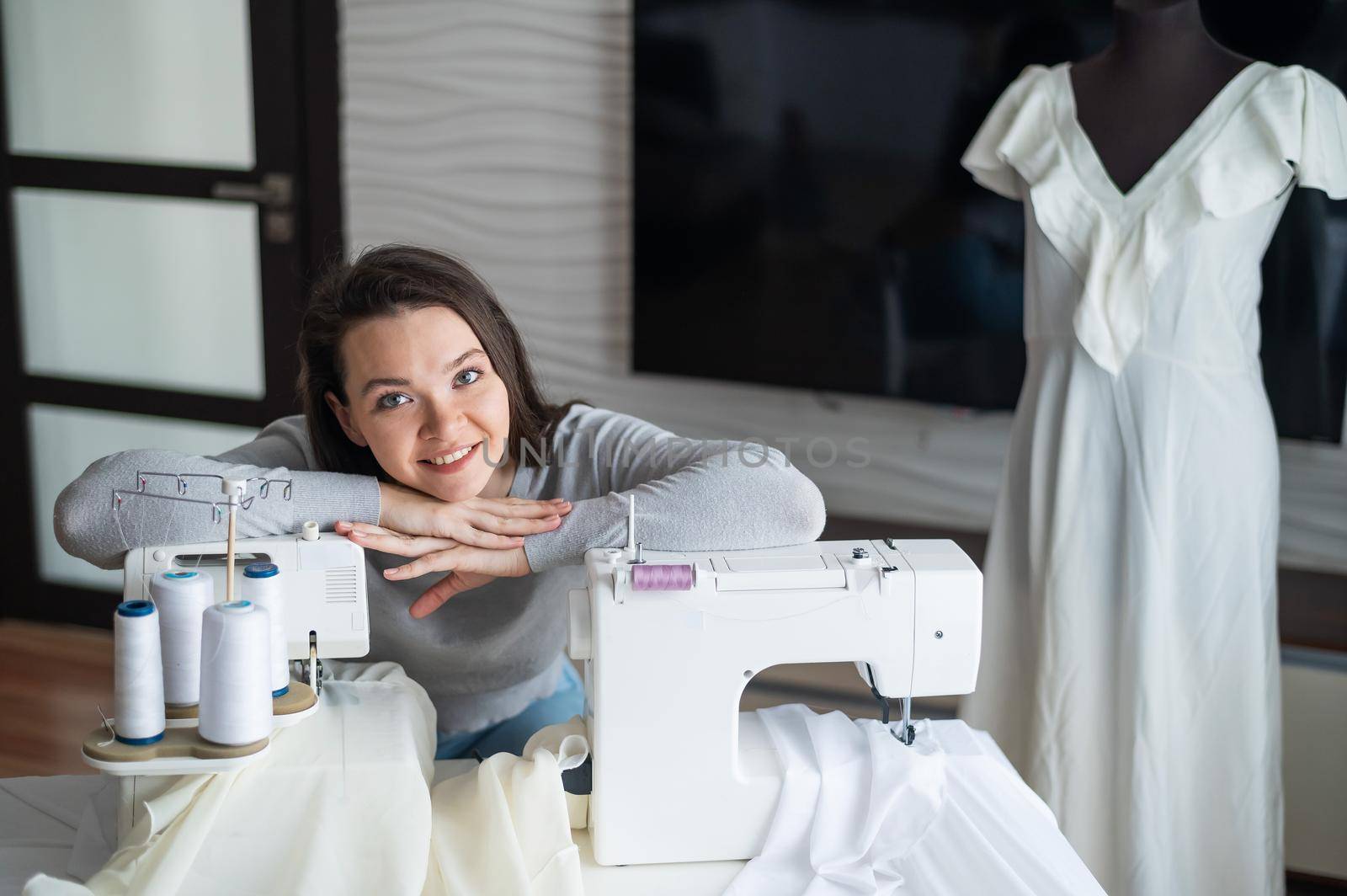 Young caucasian woman sews at home.
