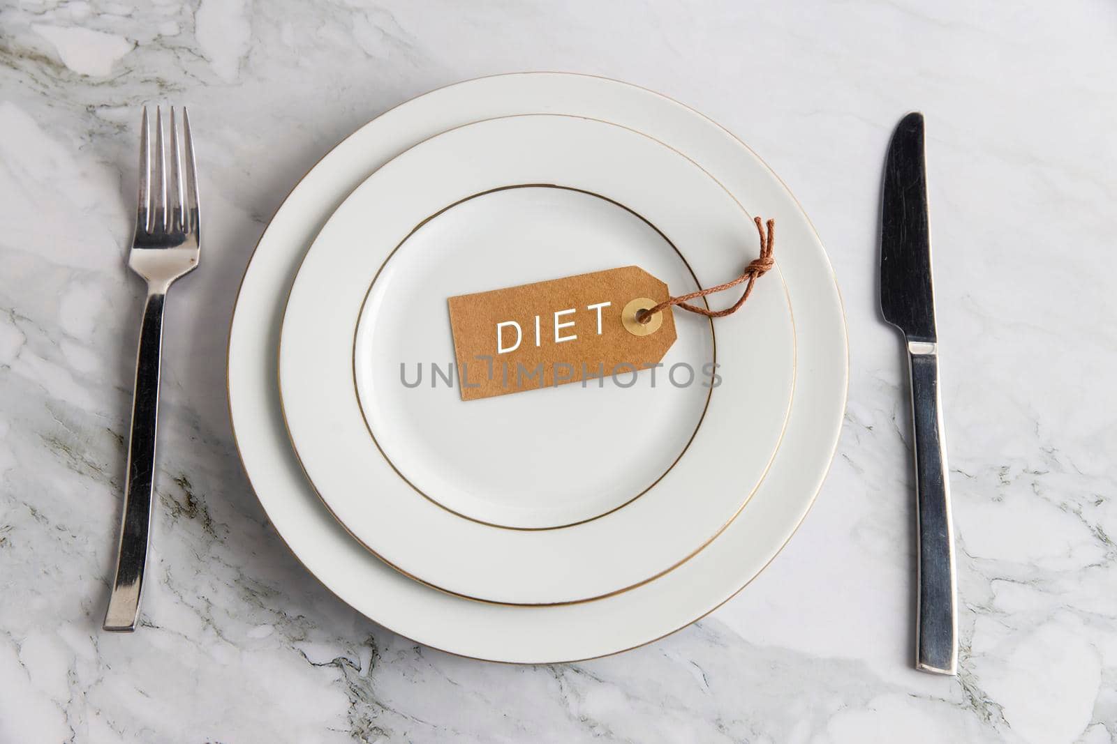 Serving two plates, spoon, fork, knife on the marble table. The concept of weight loss and diet. The concept of weight loss and diet. Label with the inscription - diet in an empty plate