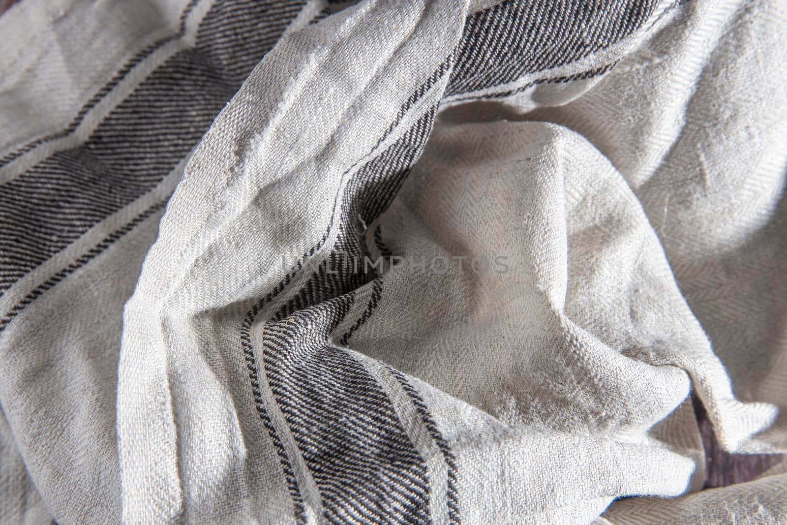 Linen gray striped towel rolled up lies on a wooden table by elenarostunova