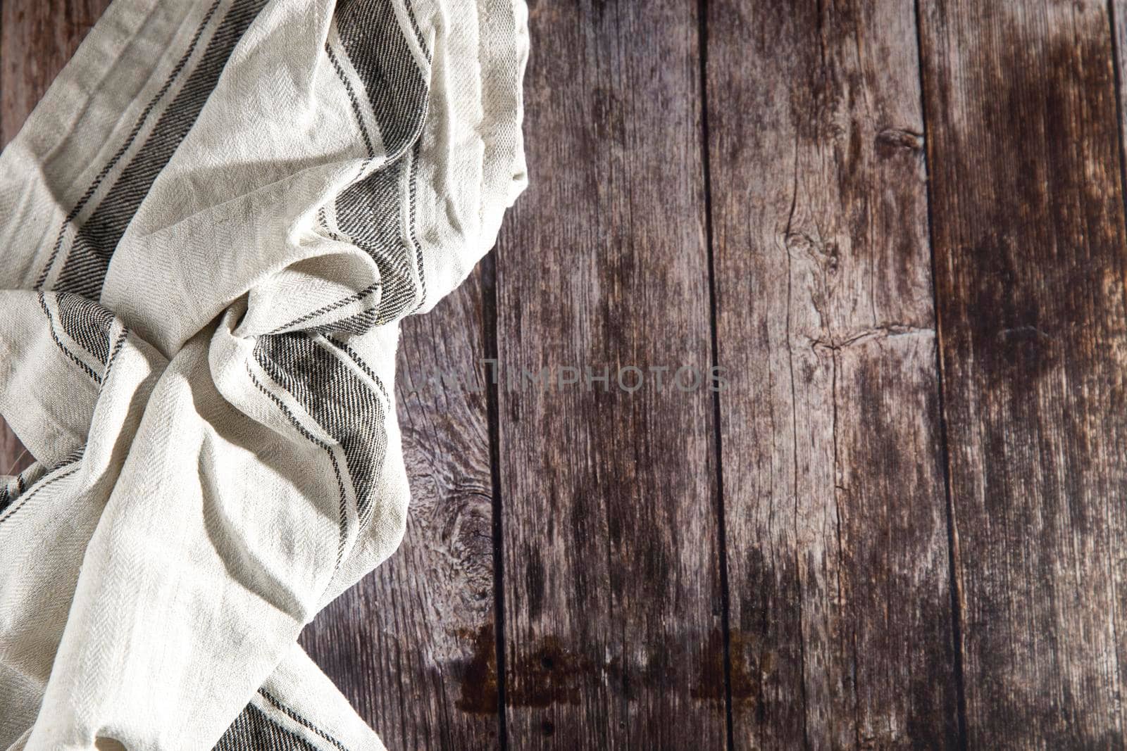 Linen gray striped towel rolled up lies on a wooden table