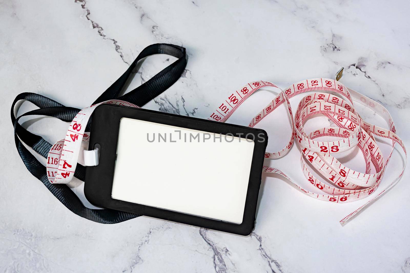 Black name tag with measure tap on white desk. Healthy and diet concept. Copy space.