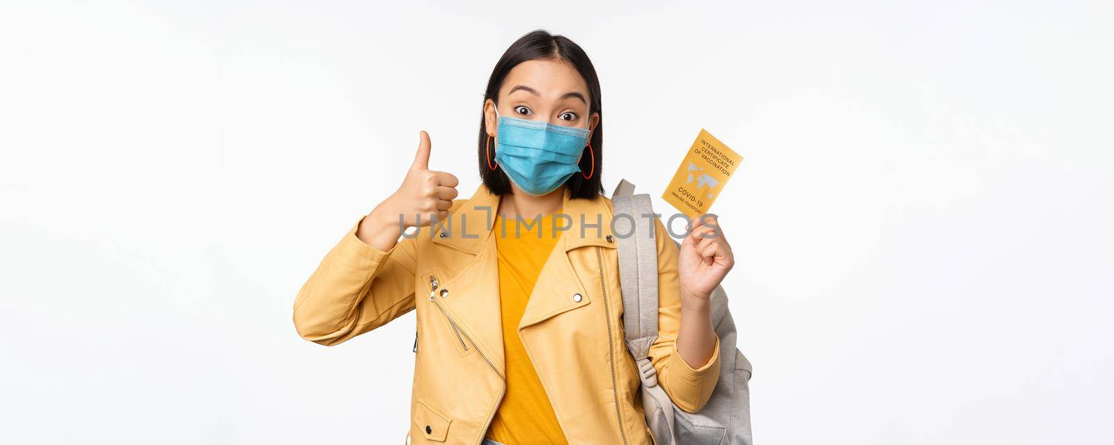 Hey you got point. Cheerful cute asian lively girl dark short haircut pointing camera finger-pistol smiling broadly, encourage friend make move, congratulate coworker good job, stand blue background.