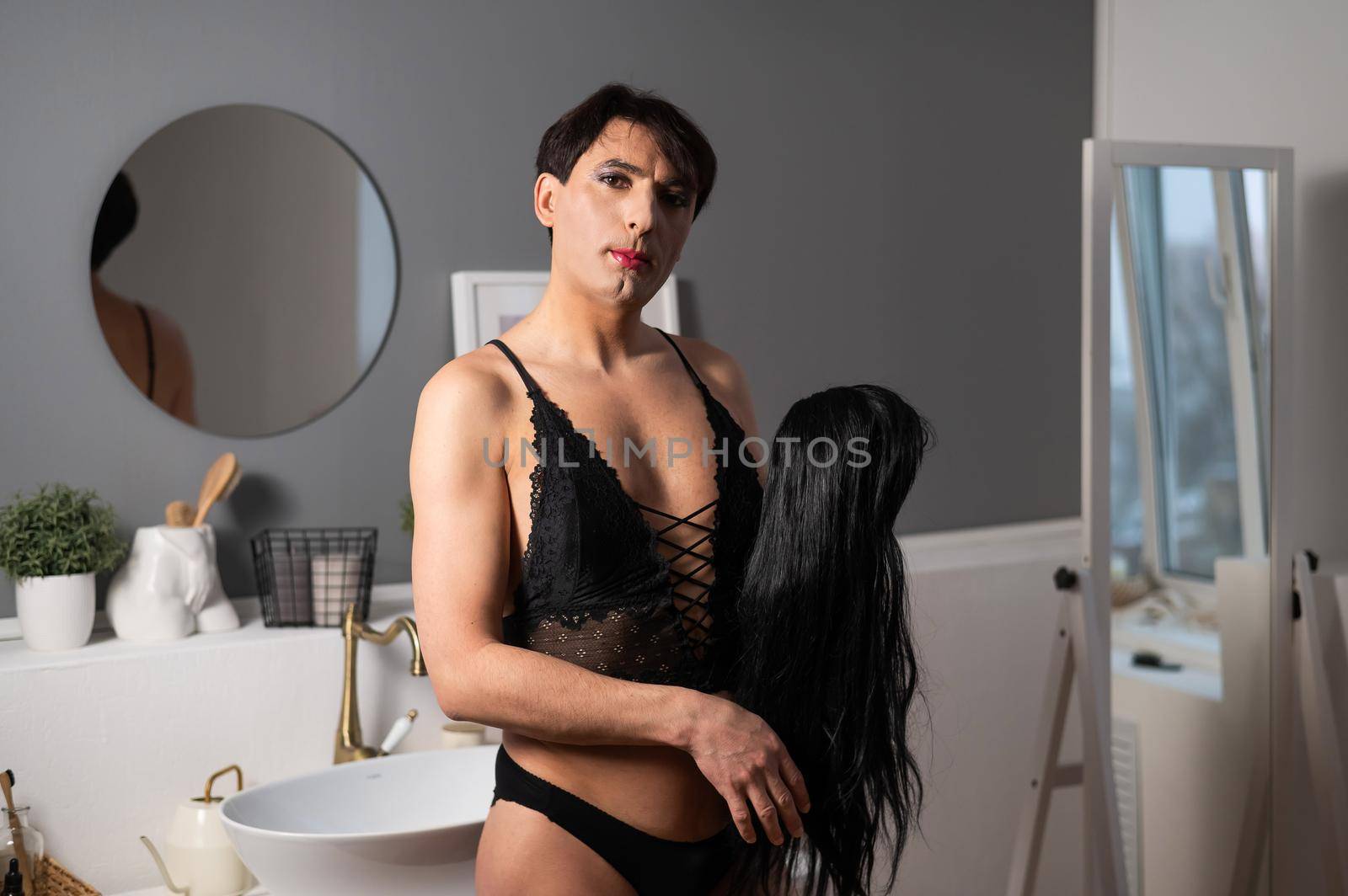 Homosexual preening in front of the mirror. A transgender man combing a wig