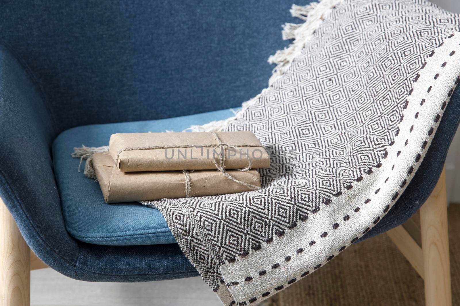 Two books wrapped in craft paper on a gray plaid on a high chair. Scandinavian style. Minimalism by elenarostunova