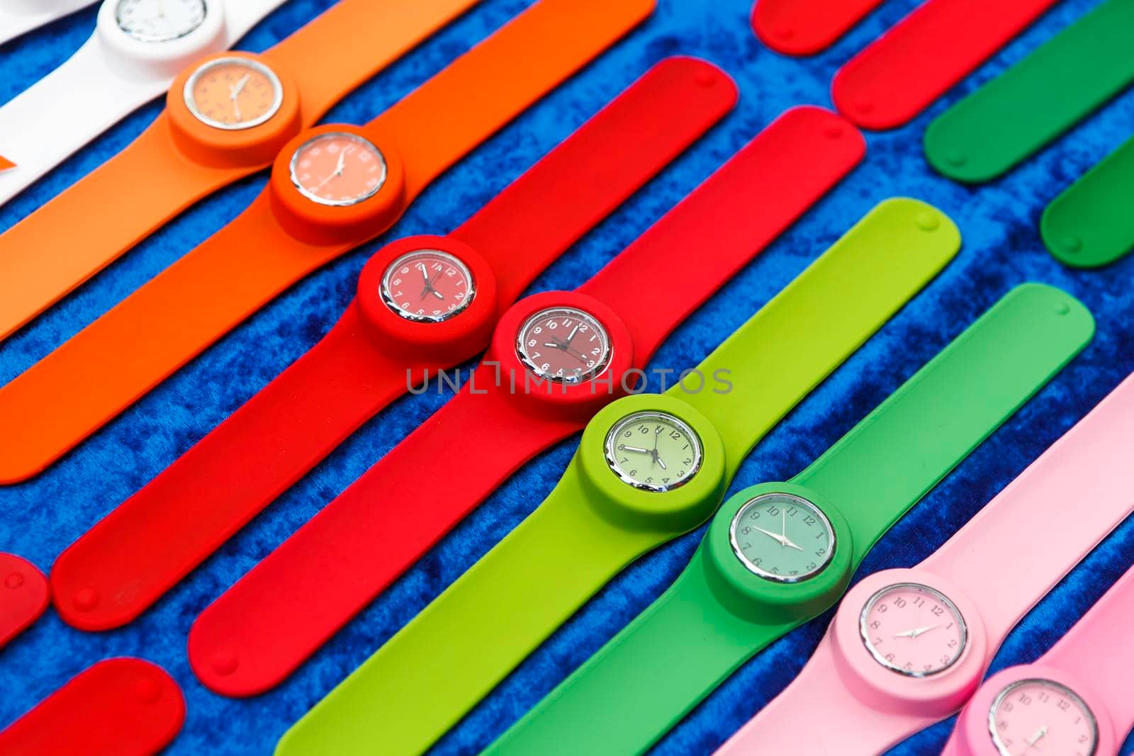 Row of multicolored clocks on display by elenarostunova