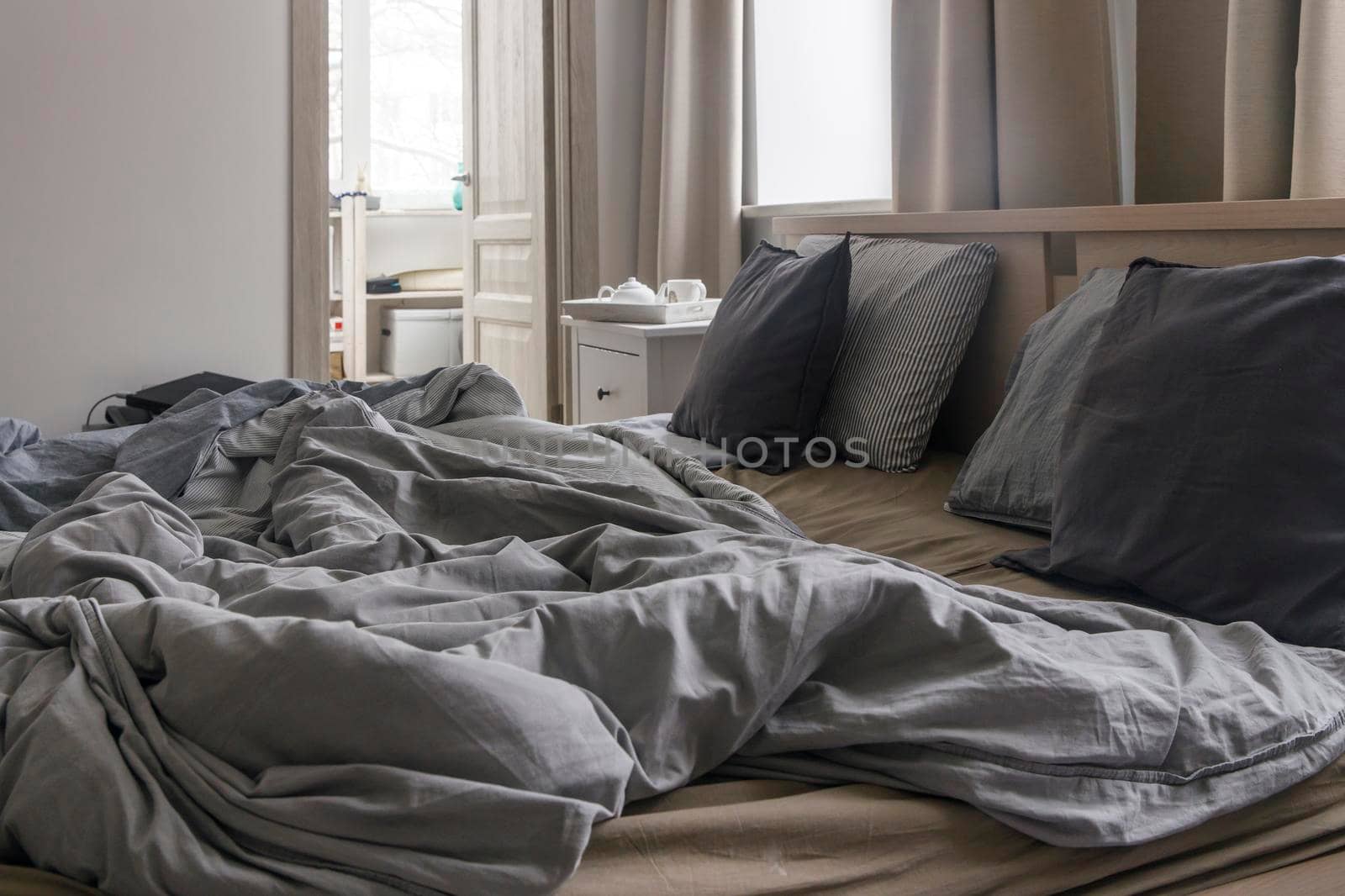 An unmade bed with two duvets in gray duvet covers. Morning concept by elenarostunova