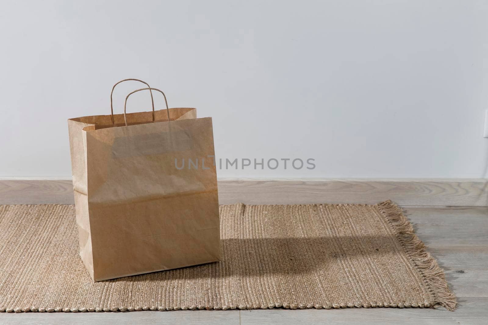 A paper bag is on a wicker rug. Copy space. Place for text by elenarostunova