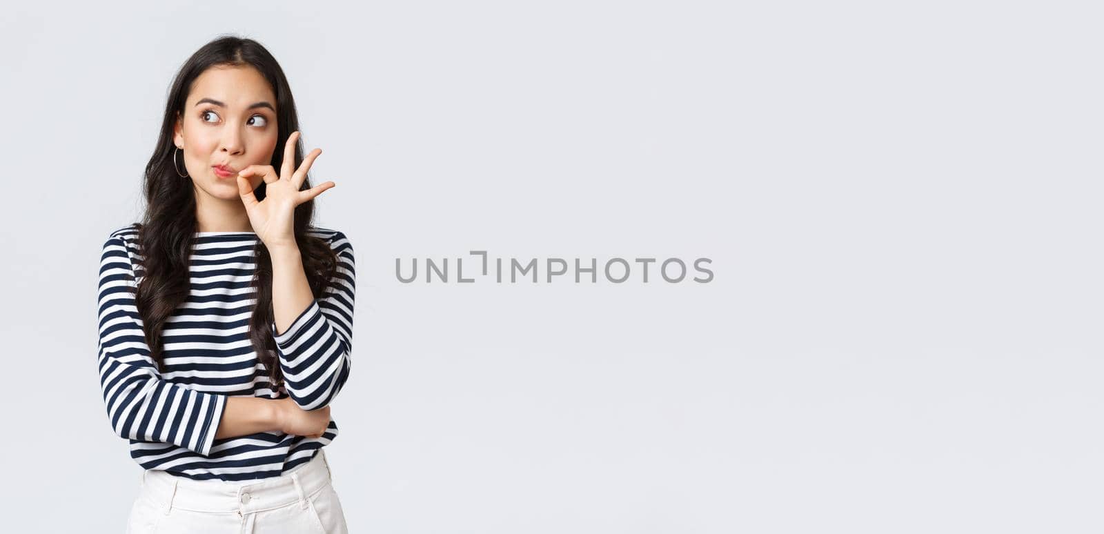 Lifestyle, beauty and fashion, people emotions concept. Serious-looking worried asian woman thinking better keep mouth shut, looking away alarmed and zipping mouth to stay quiet.