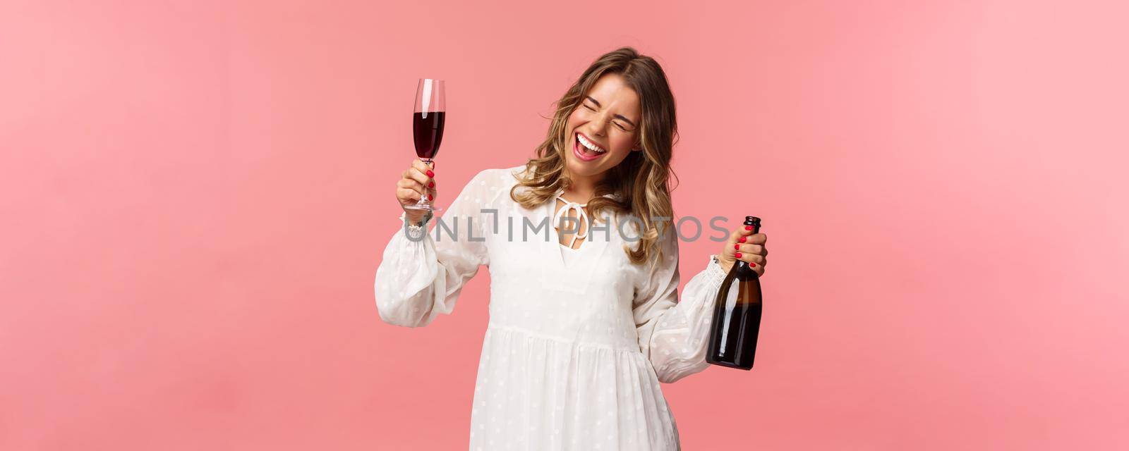 Holidays, spring and party concept. Portrait of excited and emotive good-looking blond girl dancing and celebrating, having fun saying yeah singing closed eyes, hold glass wine and bottle.