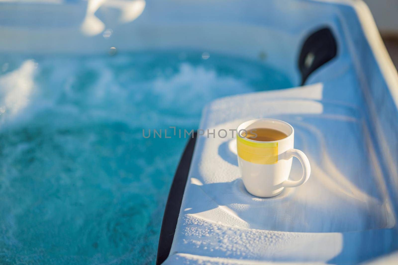 Mug with morning drink on the side of Hot tub hydromassage pool. Illuminated pool. Rest outside the city. Cottage with hydromassage pool.