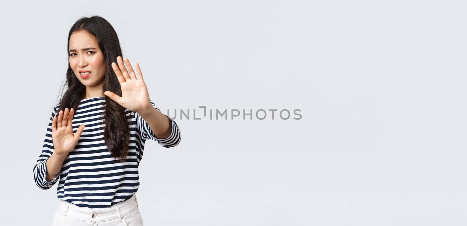 Lifestyle, beauty and fashion, people emotions concept. Woman feeling uncomfortable being photographed, asking turn camera off, raising hands up defensive, protecting face from flashlight.