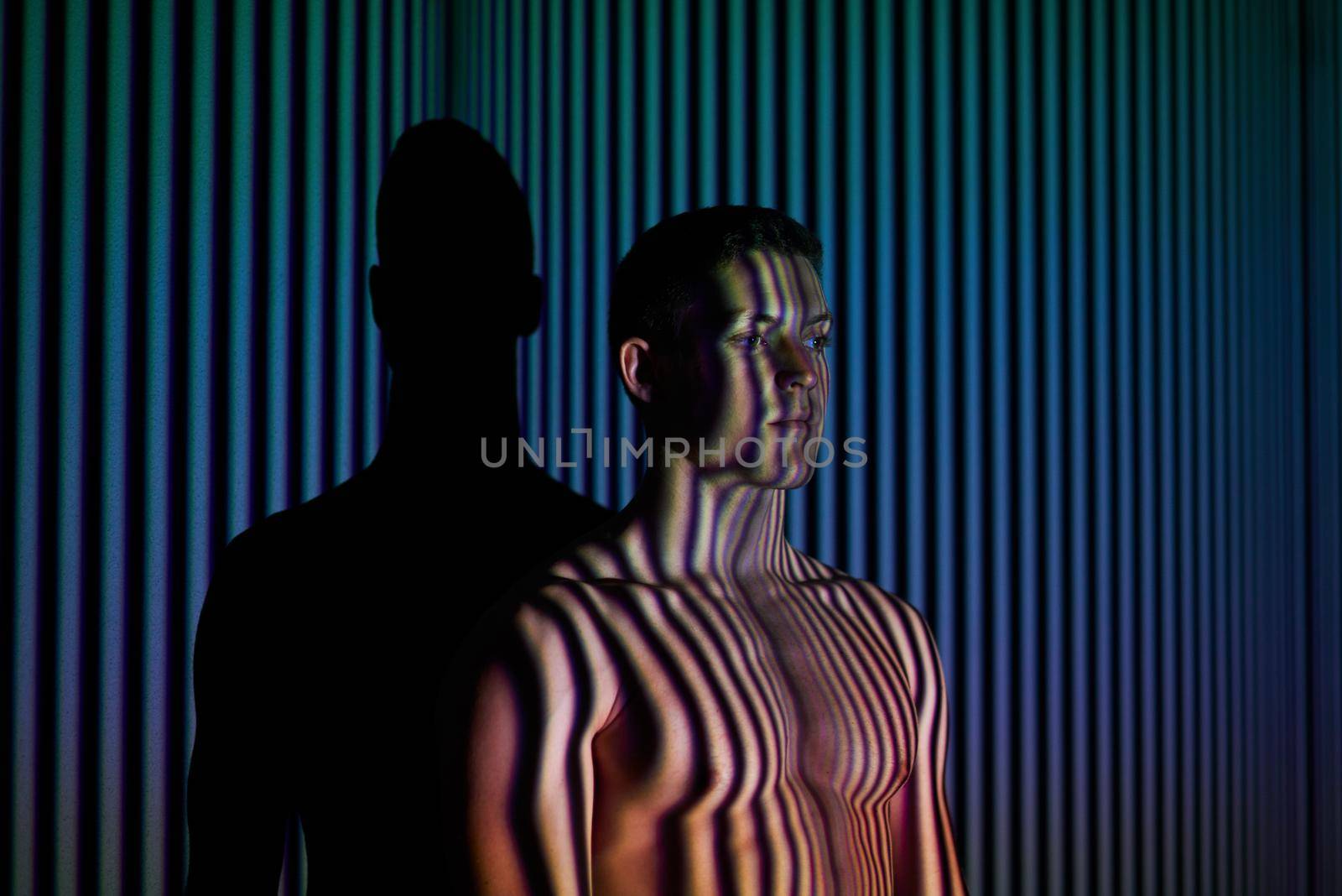 Into the mind of the man. Studio shot of a young man posing against abstract lighting. by YuriArcurs