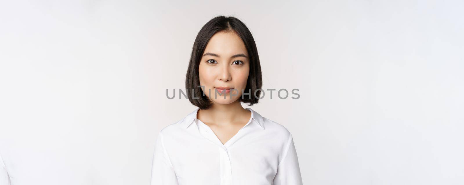 Close up portrait of korean young asian woman, professional, looking confident and assertive at camera, white background. Business people concept