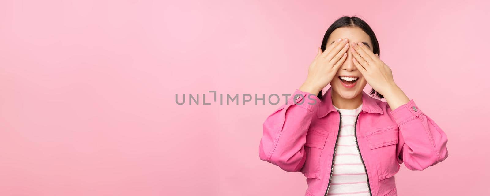 Surprise and celebration. Portrait of asian happy girl close eyes, waiting for gift, anticipating something, standing blindsided against studio background. Copy space