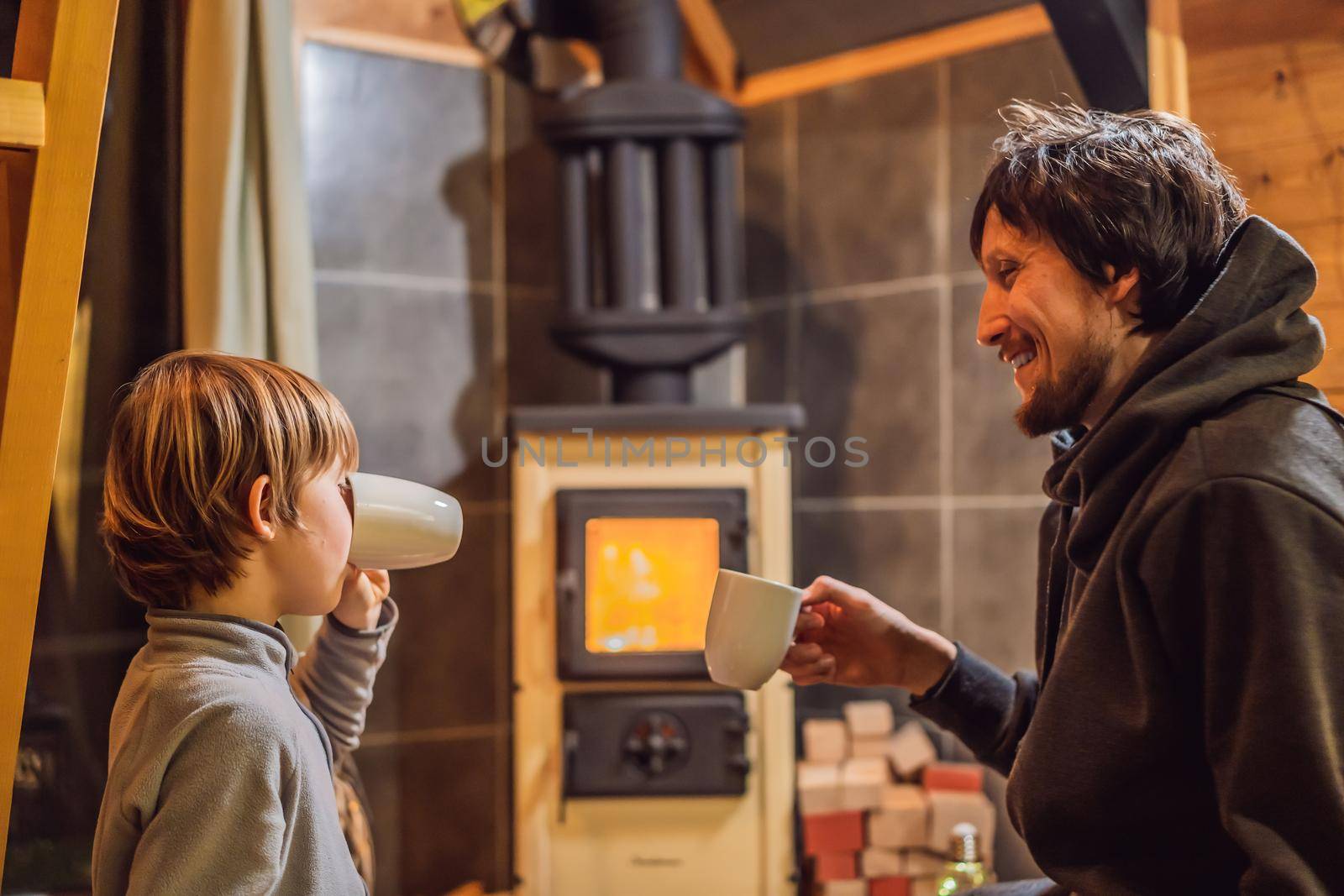 Dad and son spend time by the fireplace in Glamping. Rest in the mountains in Glamping. Cozy fireplace in a mountain house.