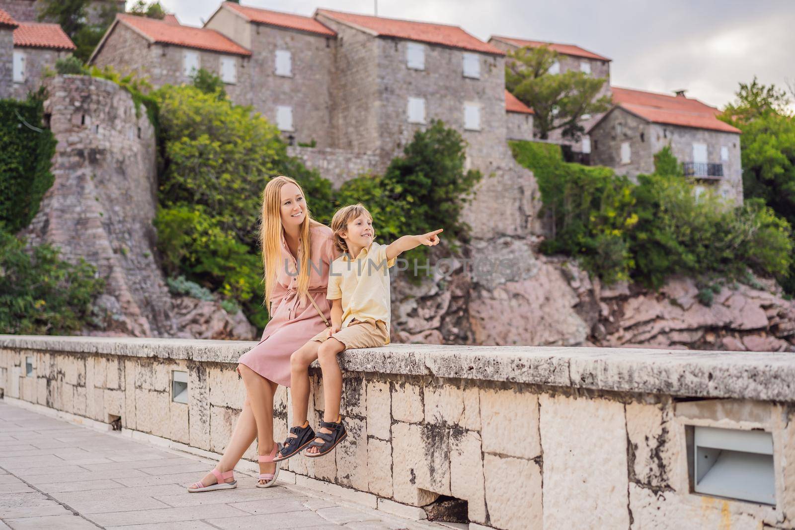 Mom and son tourists on background of beautiful view St. Stephen island, Sveti Stefan on the Budva Riviera, Budva, Montenegro. Travel to Montenegro concept.
