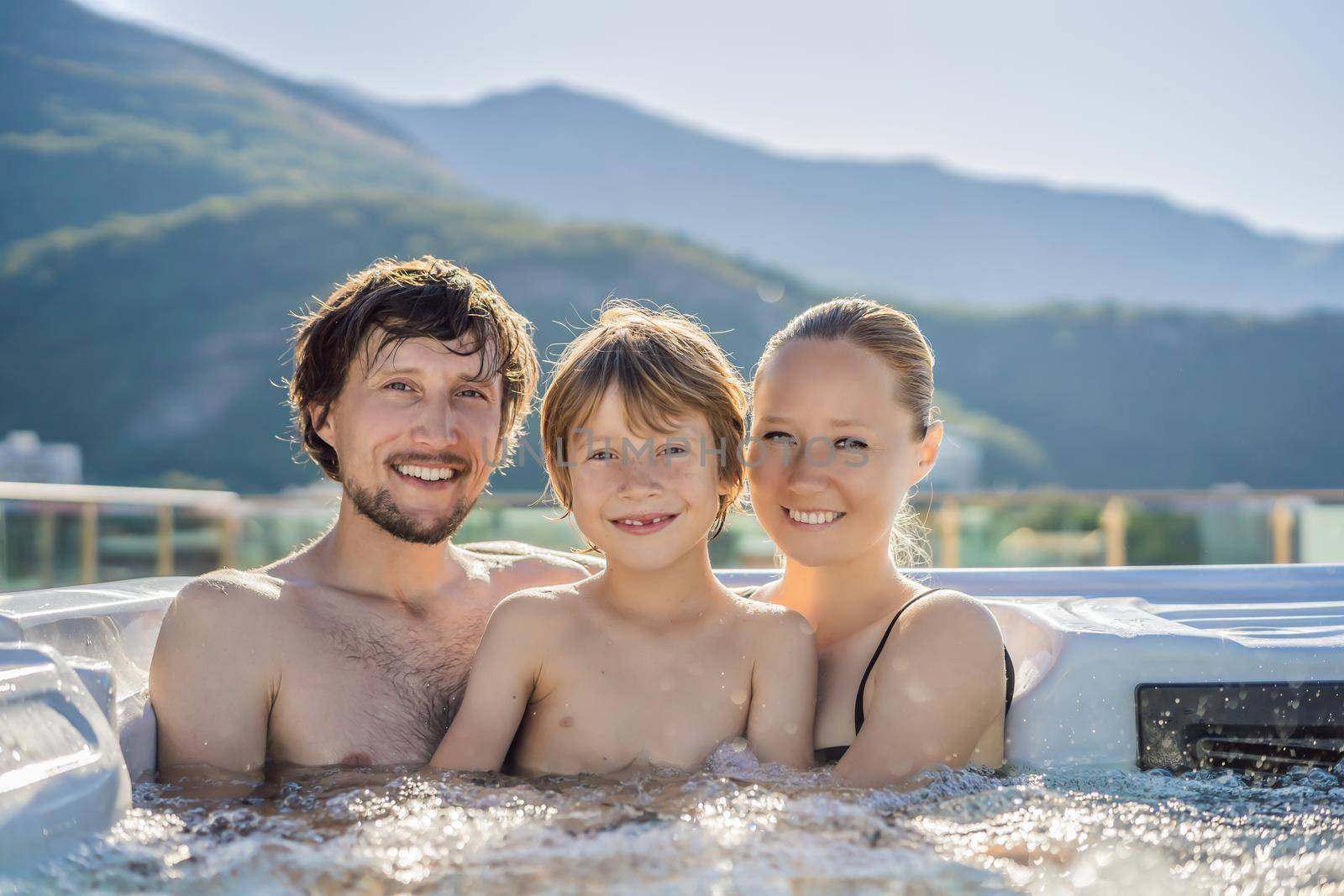 Portrait of young carefree happy smiling happy family relaxing at hot tub during enjoying happy traveling moment vacation. Life against the background of green big mountains.